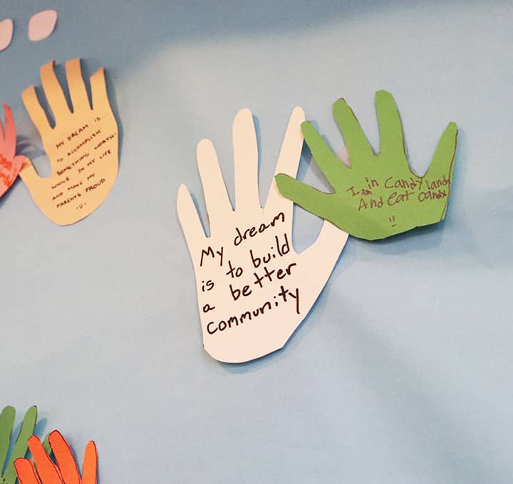 Paper craft hands posted on the wall with dreams written on them.