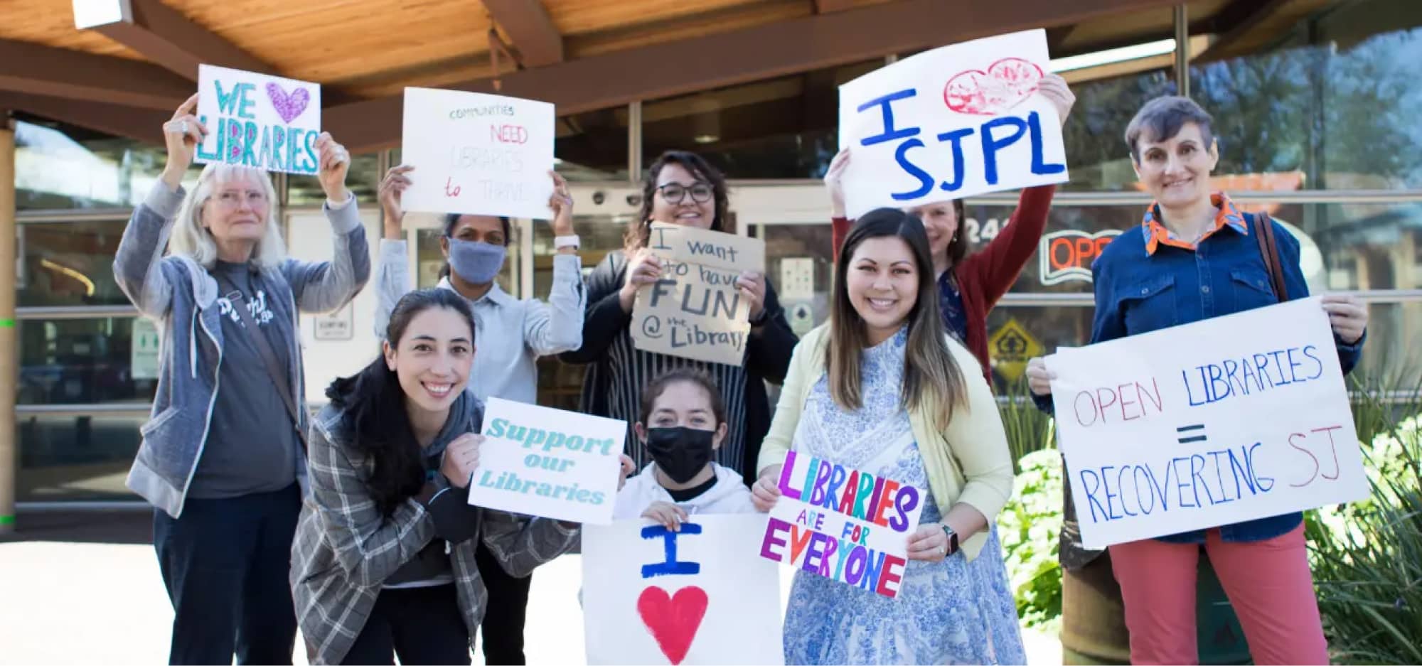 Group of library goers holding handmade 'I heart SJPL' signs.