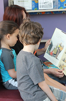 Parent reading to two young children.